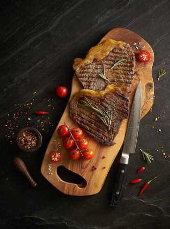 steak on wooden board with knife on black backgroundの写真素材