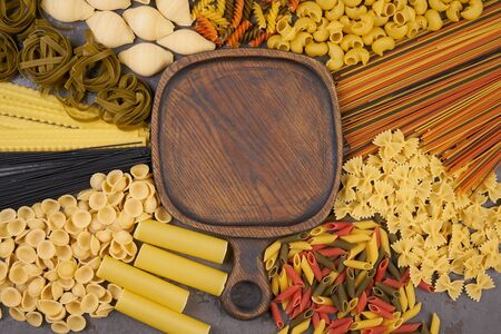 Pasta assorti on gray background with wooden trayの写真素材