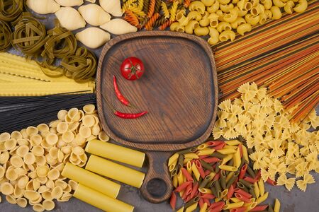 Pasta assorti on gray background with wooden trayの写真素材