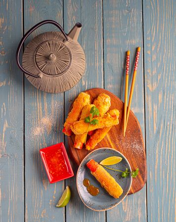 fish fingers on a wooden tray with teapotの写真素材