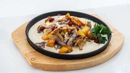 fried potatoes with chanterelles in a creamy sauce on whiteの写真素材