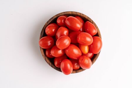cherry tomatoes on wooden plate on whiteの写真素材
