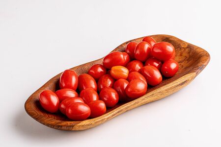 cherry tomatoes on wooden plate on whiteの写真素材