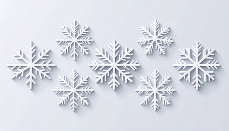 Several white snowflakes of different sizes are arranged randomly on a pale surface. Long shadows fall from the snowflakes, suggesting a light source from above.の素材