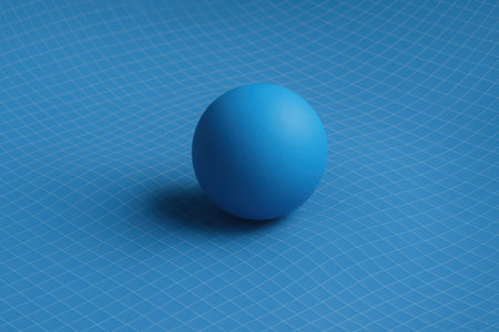 A minimalist composition featuring a vibrant blue ball centered on a blue textured surface. The round object casts a gentle shadow, emphasizing its spherical form against the subtle pattern of the background, creating a serene and cohesive blue theme.の素材