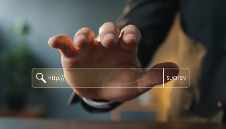 A human hand, dressed in professional attire, reaches out towards a glowing, transparent virtual search bar floating in a blurred, contemporary office or workspace environment. The interactive interface displays various digital symbols and numbers, suggesting a complex data exploration or information retrieval process. This visual metaphor represents advanced technology, internet connectivity, and the seamless integration of digital tools into everyday professional life, emphasizing innovation in user experience and access to vast amounts of information. The shallow depth of field keeps the focus sharply on the hand and the interactive display.の素材