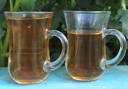 Glass turkish glasses with tea on a blue wooden table in the gardenの写真素材