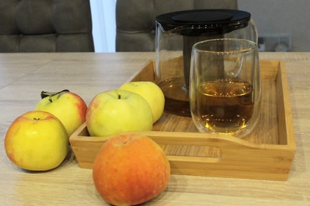 Five apples on a tray with tea and on a wooden tableの写真素材