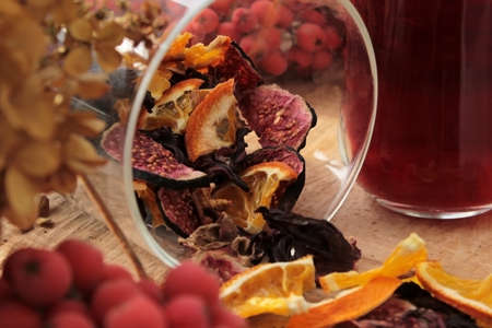 Tea with dried figs, pomegranate leaves and orange slices in a jar close-upの写真素材