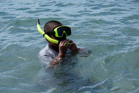Kolaka, Indonesia-August 16,2020: A boy learning to snorkel on the beachの写真素材