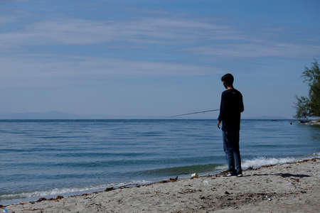 Kolaka, Indonesia-August 16,2020: A man fishing beside the seaのeditorial素材