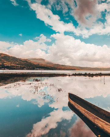 Wooden boat on the lake with reflection of clouds in the waterの写真素材