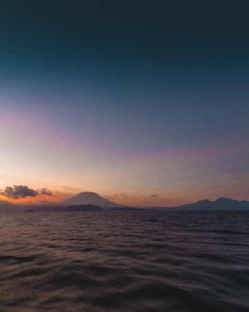 Sunset over the sea and mountains in the background, Bali, Indonesiaの写真素材