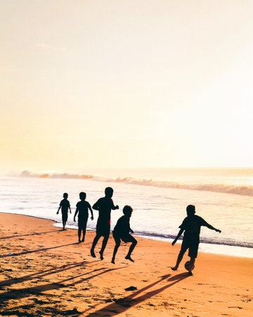 Silhouette of children running on the beach at sunset time.の写真素材