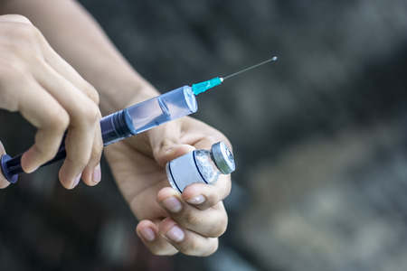 Syringe, medical injection, bottle, ampule in hand, palm or fingers. Medicine plastic vaccination equipment with needle. Nurse or doctor. Liquid drug or narcotic. Health care in hospitalの写真素材