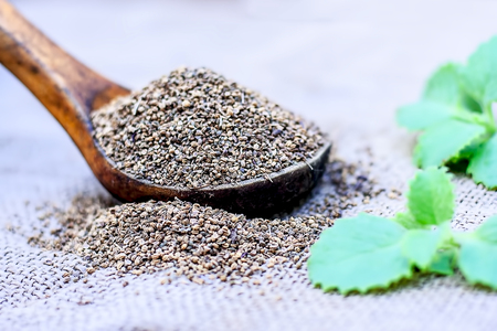Trachyspermum ammi, Ajwain seeds in a wooden scoop with some leaves on a gunny background.の写真素材