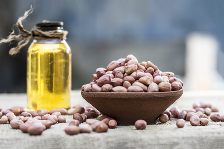 [Arachis hypogaea] Raw Groundnut in a clay bowl with groundnut oil on a gunny background.の写真素材