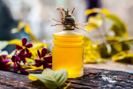 Combretum indicum,Rangoon creeper's oil in a glass bottle on rustic wooden surface with it's flowers.の写真素材