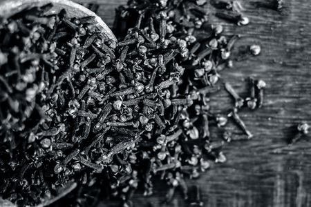 Raw organic cloves,Syzygium aromaticum in a clay bowl on the wooden surface.