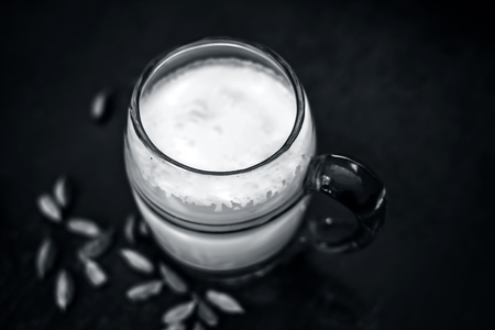 Sweetened milk with some green cardamoms on brown wooden surface.の写真素材