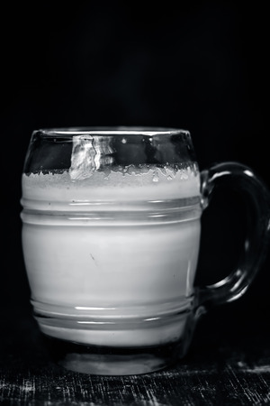 Unsweetened milk in a transparent glass on wooden surface.の写真素材