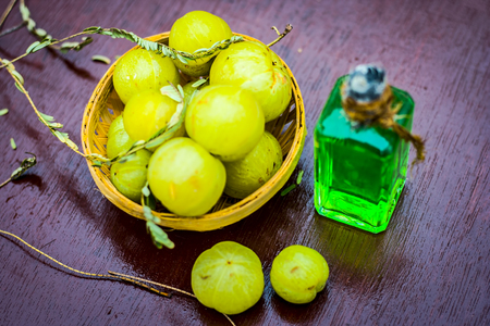 Close up of raw Phyllanthus emblica or Indian goose berry in a basket with its oil beneficial or helps in regrowing hairs.の写真素材