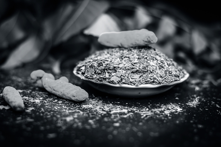 Powder of Indian lilac,Azadirachta indica in a glass plate with its leaves and raw underpowered turmeric.の写真素材