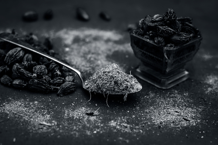 Raw black cardamom on a bluish surface with its powder.;の写真素材