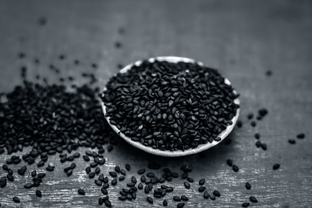 Close up of black sesame seed,Sesamum indicum in a small plate on a wooden surface.の写真素材