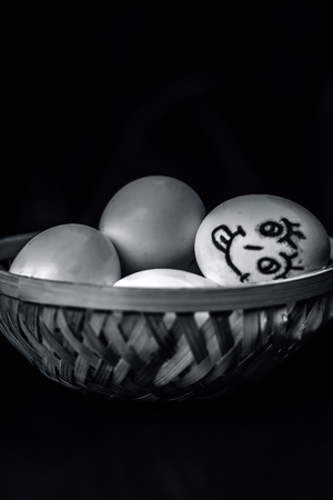 Close up of eggs of easter in a traditional basket with one egg drawn a funny face.の写真素材