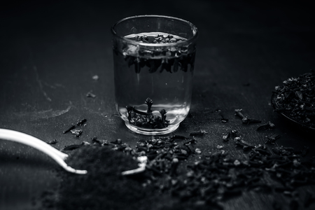 Close up of cloves,Syzygium aromaticum in a plate with its powder in a fork and water in a transparent glass.の写真素材