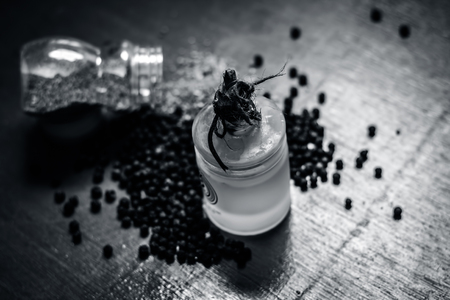 Close up of oil of black pepper,Piper nigrum with raw black pepper and powder on a wooden surface.の写真素材