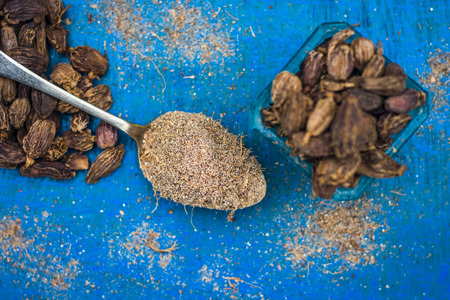 Close up of spice Black cardamom with its powder on blue wooden surface.の写真素材