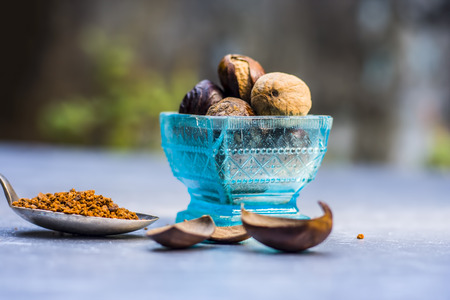 Close up of Nutmeg,Jaiphal,Myristica fragrans in a glass container with its powder on wooden surface.の写真素材