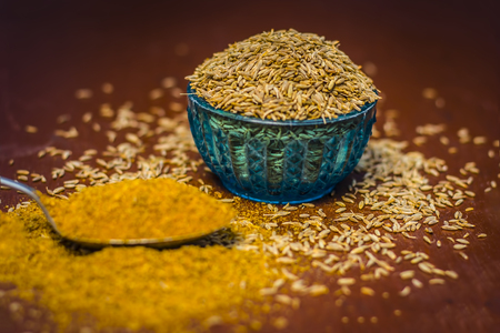 Cumin,Cuminum cyminum and powder on wooden surface.の写真素材