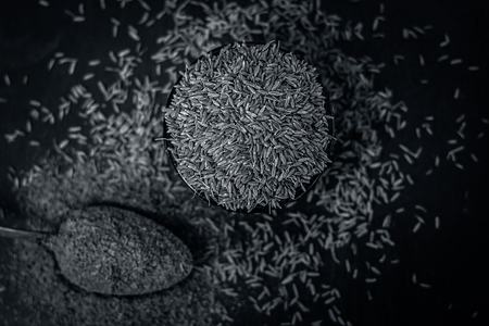 Close up of cumin,Cuminum cyminum and its powder in a spoon on a wooden surface.の写真素材