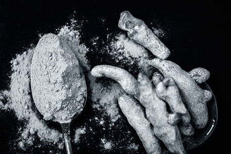 Turmeric,Curcuma longa and its powder on a wooden surface.;