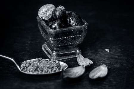 Close up of Nutmeg,Jaiphal,Myristica fragrans in a glass container with its powder on wooden surface.の写真素材