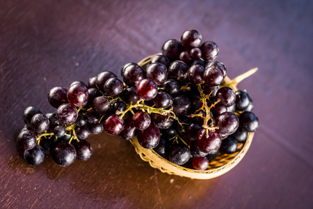 Close up of Grapes,Vitis vinifera in a basket on a brown wooden surface.の写真素材
