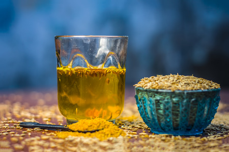 Cumin,Cuminum cyminum with its powder and its extracted water on brown wooden surface.の写真素材