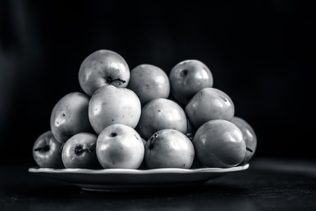 Fresh ripe Indian plum,Bor,Oemleria cerasiformis or Indian jujubs in a white glass plate on wooden surface.の写真素材