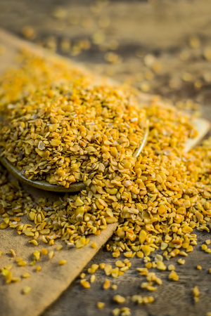 Crushed Fenugreek seeds,Trigonella foenum-graecum seeds,methi ke koriya in a bowl on wooden surface.の写真素材