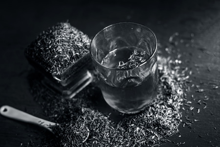 Black cumin seeds,shah jerra,Nigella sativa  and its extracted water in a transparent glass on brown...