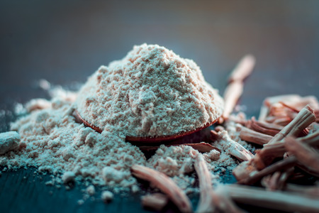 Ayurvedic herb satavari,Asparagus racemosus with its powder and root in a bowl on brown wooden surface in dark gothic colors for healthy female reproductive system, for an good reproductive system.の写真素材