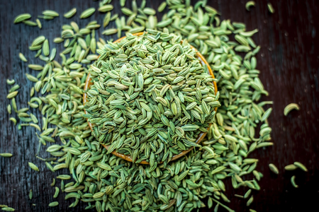 Raw dried fennel seeds or variyali or Foeniculum vulgare in a brown plate on wooden surface.の写真素材