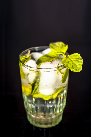 Fresh mint water with ice cubes on a white surface with fresh organic mint leaves.