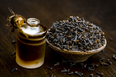 Close up of black peppercorns or kali mari on wooden surface with its extracted herbal beneficial oil.の写真素材