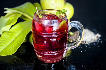 Close up of popular Indian shrabat of Guava with sugar and masala in a glass with raw fresh guava on wooden surface.の写真素材