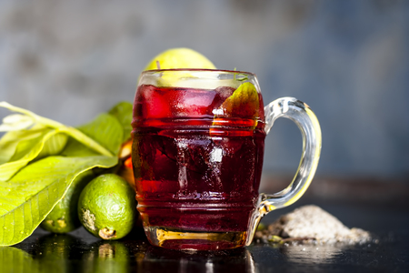 Close up of popular Indian shrabat of Guava with sugar and masala in a glass with raw fresh guava on...