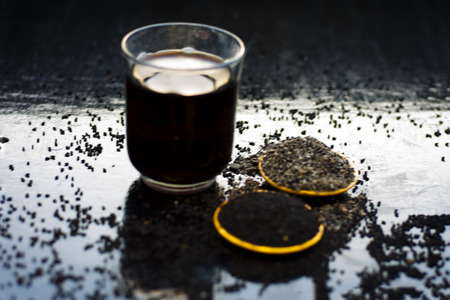 Close up of kalonji or roman coriander with grape juice and its powder on wooden surface beneficial...
